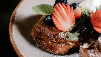 Un dessert composé de fraises, de myrtilles et saupoudré de sucre glace, présenté dans une assiette.