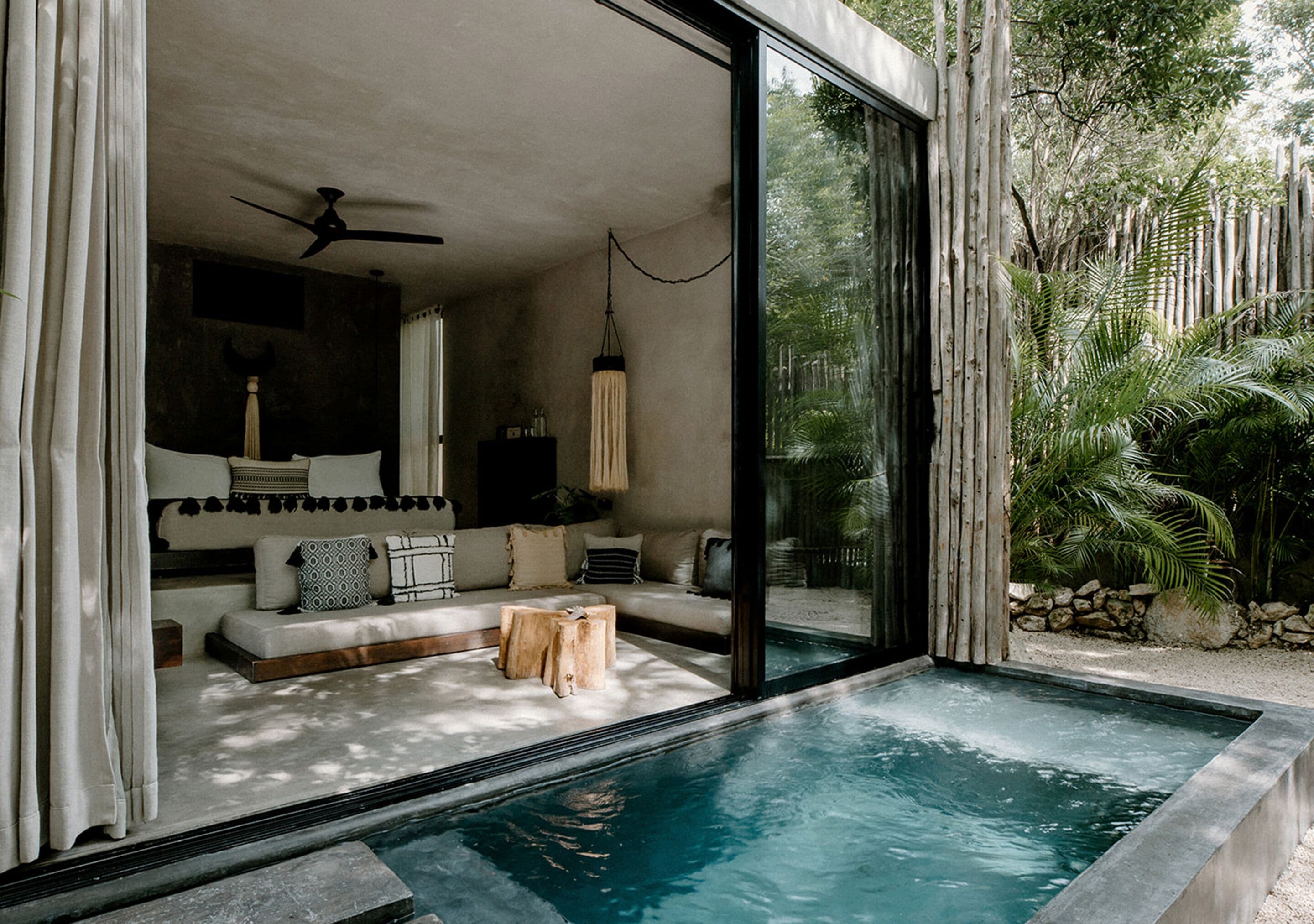 A modern interior with a glass-enclosed pool, a sofa with cushions, and a ceiling fan.