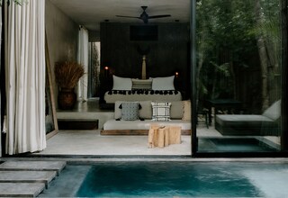 A modern bedroom with a large bed, a ceiling fan, and a view of a swimming pool.