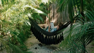 Relax in a hammock suspended between palm trees, surrounded by lush tropical foliage and a serene atmosphere.