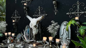 A rustic outdoor altar with religious statues, candles, and a skull.