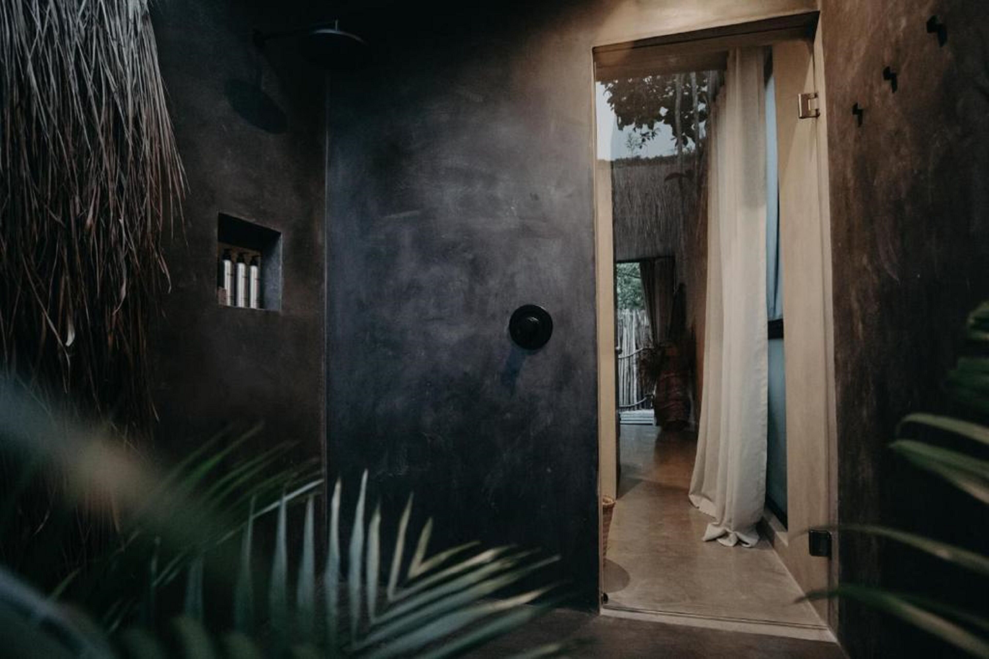 A hallway with a textured wall, a small window, and a door leading to another room.