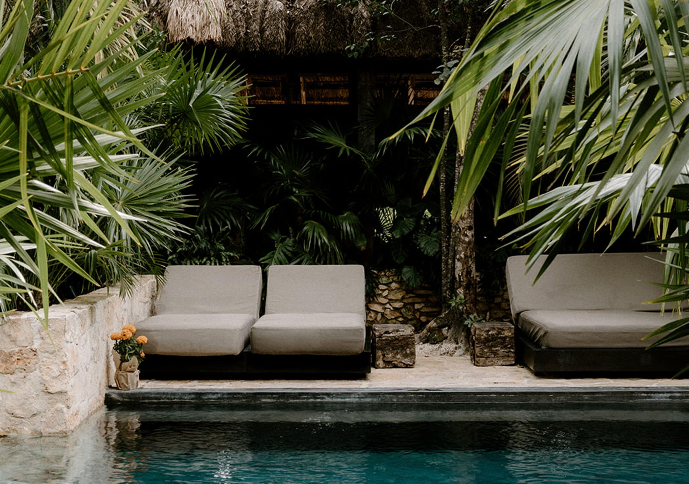 A poolside area with two beige sofas and a stone wall.