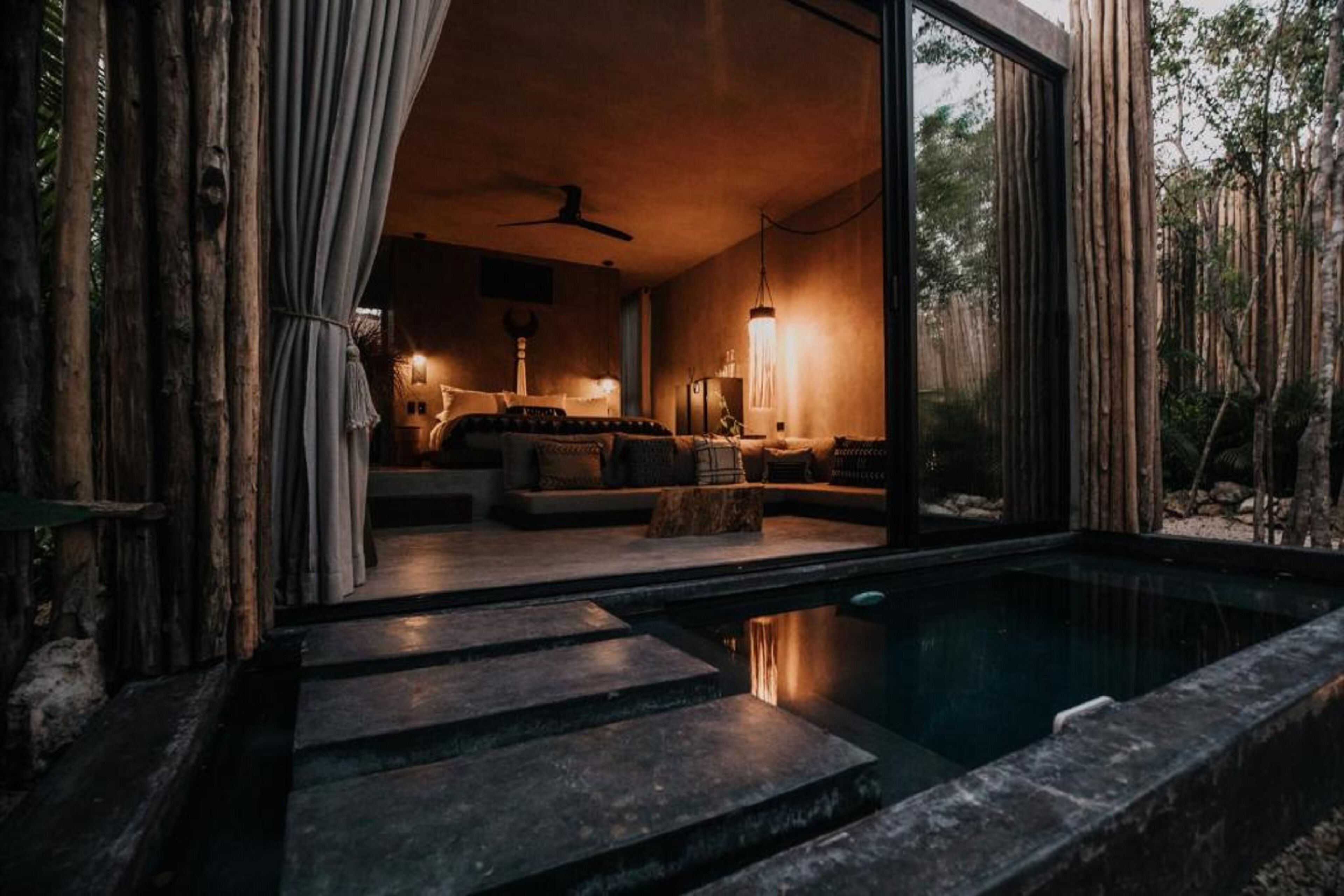 Un intérieur moderne avec une piscine, des escaliers en pierre et une vue sur la forêt.