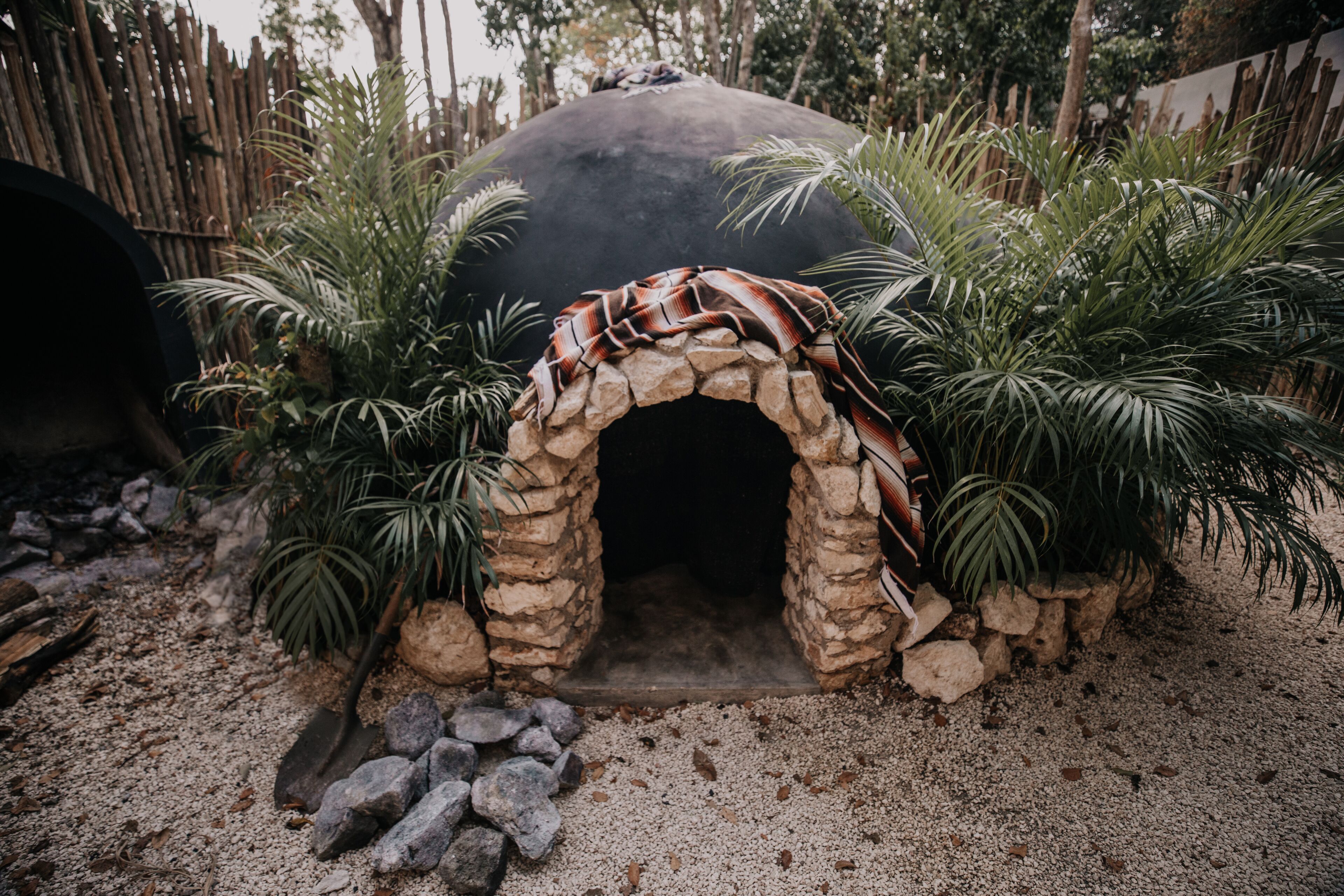A stone archway with a blanket draped over it, surrounded by palm plants.