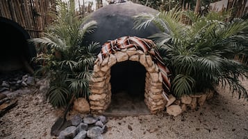 A stone archway with a blanket draped over it, surrounded by palm plants.