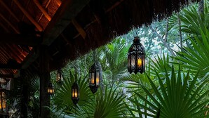 A covered outdoor area with hanging lanterns, lush tropical plants, and a thatched roof structure. - Hotel Bardo Adults Only (Tulum)