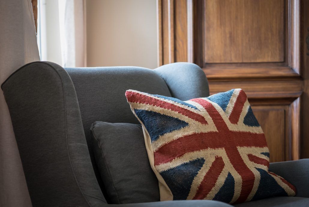 Ein graues Sofa mit einem Kopfkissen mit Union-Jack-Muster.