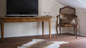 A room with a wooden desk, a television, two wine glasses, and a leather chair. - Hotel Eifellust (Schalkenmehren)