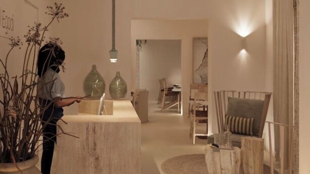 A modern interior with a wooden block counter, a dining area with chairs, and a large vase with dried plants.