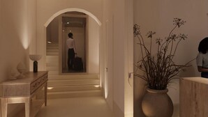A hallway with a staircase, a desk with a lamp, and a vase with plants.