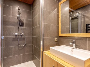 Une salle de bain avec une douche, un lavabo et un miroir.