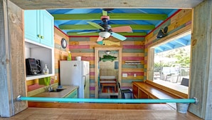 Een compacte keuken met een kleurrijk houten interieur, een plafondventilator en uitzicht op de omgeving.