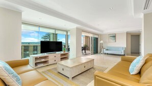 A spacious living room with a large TV, comfortable seating, and a view of the outdoors. - Unit 14  - 3 Bed Garden View (TERRIGAL)