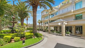 A hotel with a landscaped garden, palm trees, and a fountain. - Unit 14  - 3 Bed Garden View (TERRIGAL)