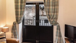 A room with a black door, plaid curtains, a television, and a lamp. - White Lanes by Pureserviced (Plymouth)