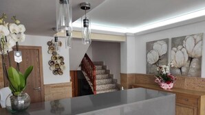 A modern kitchen with a large island, a wooden staircase, and decorative wall art. - Hotel Vista Sol (Capdepera)