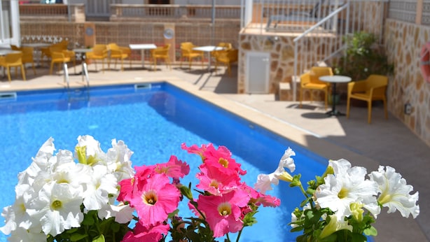 A pool area with yellow chairs and tables, surrounded by a stone wall and a staircase. - Hotel Vista Sol (Capdepera)