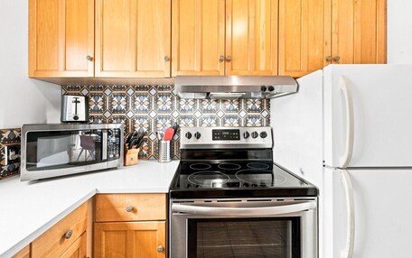 A kitchen with wooden cabinets, a microwave, a stove, and a refrigerator.