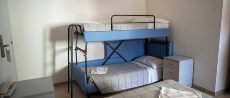 A bunk bed with a desk and a small cabinet, a telephone on a table, and a window with blinds.