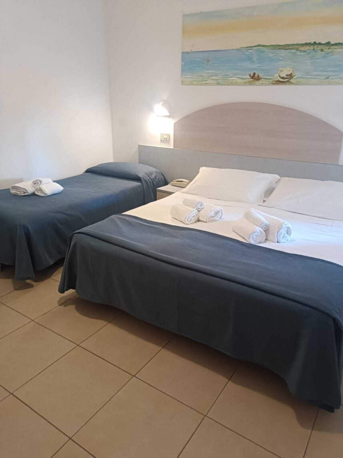 Habitación de hotel con dos camas, cada una con toallas ordenadamente dobladas.