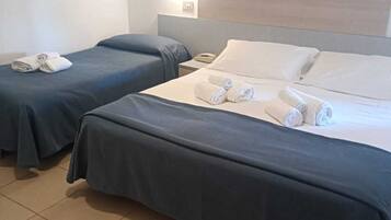 Habitación de hotel con dos camas, cada una con toallas ordenadamente dobladas.