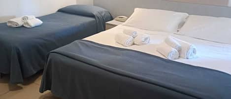 Habitación de hotel con dos camas, cada una con toallas ordenadamente dobladas.