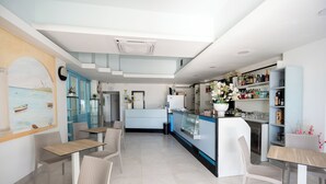Un restaurante moderno con una zona de bar, arreglos de asientos y una cocina visible al fondo.