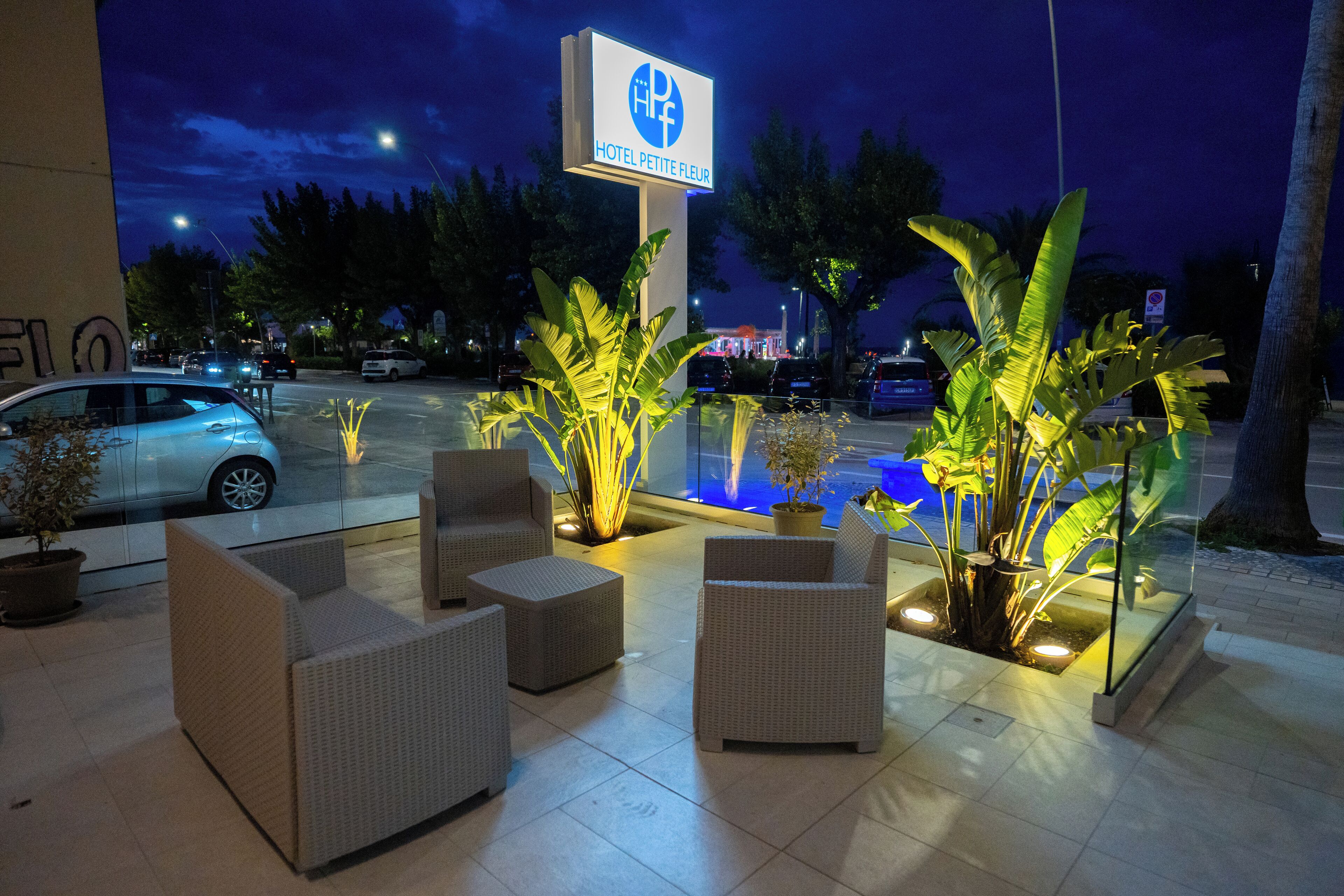 A hotel sign, outdoor seating area, and a pool.