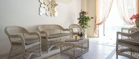 A room with wicker furniture, a coffee table, and a potted plant.