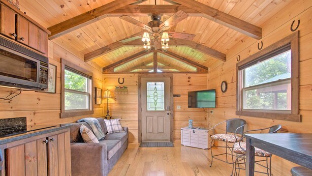 A cozy cabin interior with wooden walls, a kitchen area, a dining table, and a comfortable seating area. - Year-Round Adventure! Rustic Cabin in Mill Spring (Mill Spring)