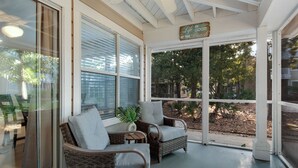 Un solárium con mobiliario de mimbre, ventanas amplias y un ventilador de techo.