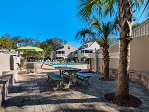 A pool area with lounge chairs, a table, and a palm tree. - Hidden Dunes Cottages 2-Bedrooms (Miramar Beach)