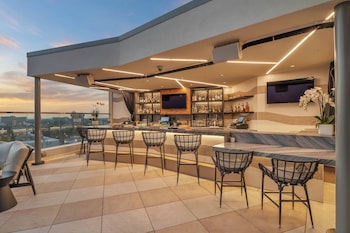 A bar area with seating and a pool in the foreground. at JW Marriott Anaheim Resort