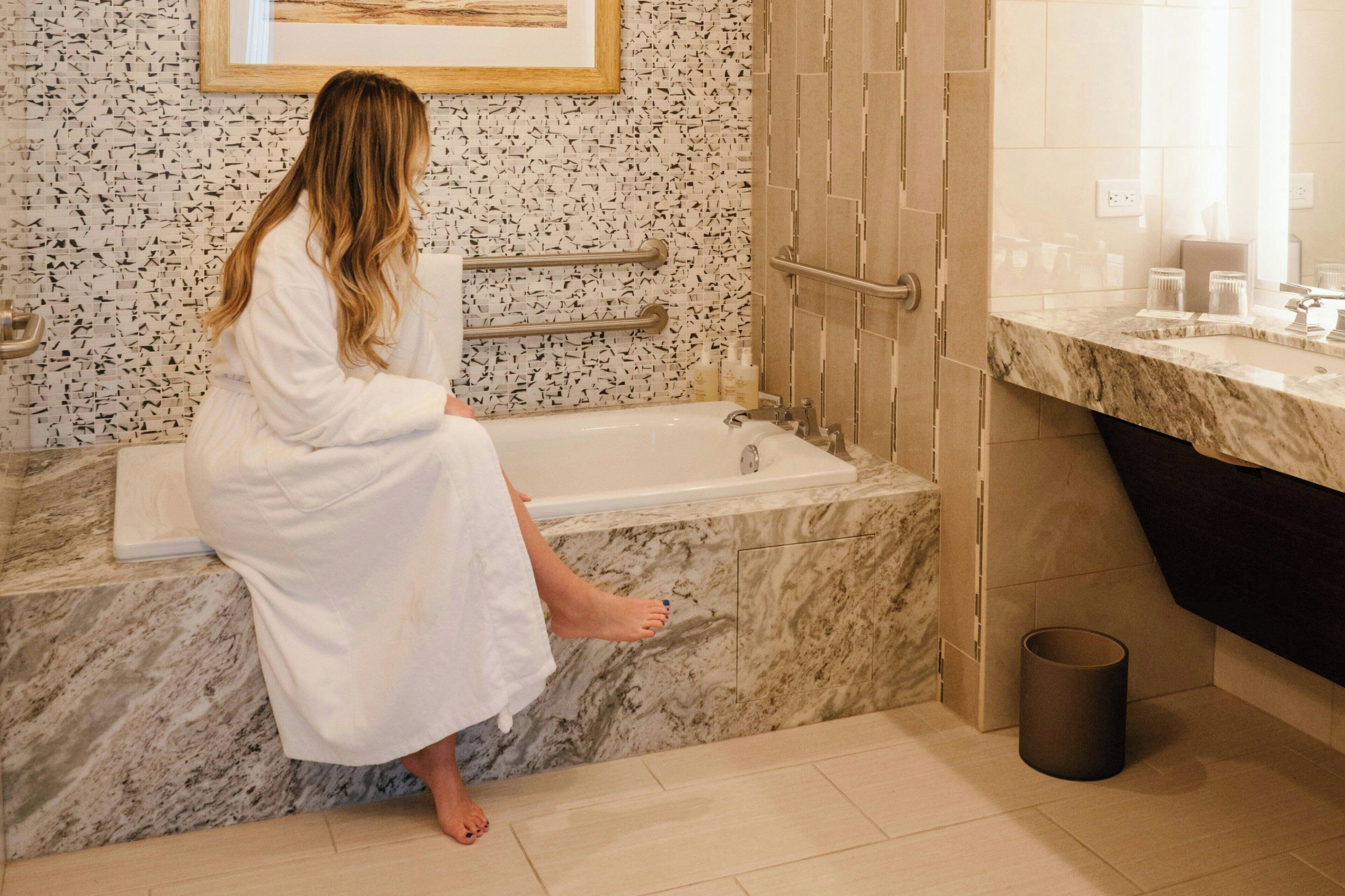 Ein Badezimmer mit einer Badewanne, Marmorplatte und einer gefliesten Wand.