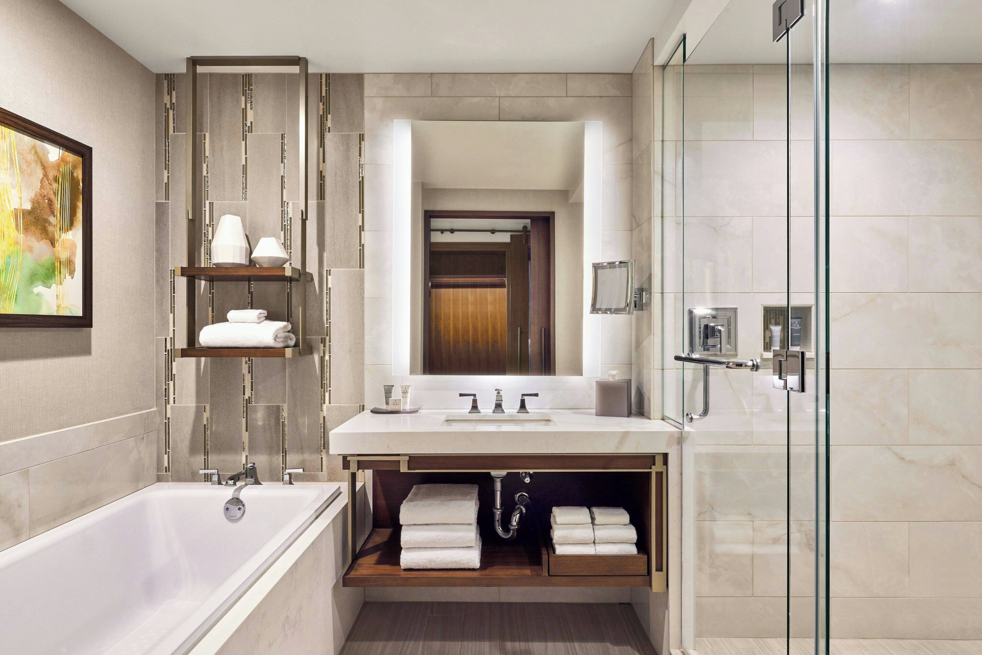 Un bagno moderno con vasca, box doccia in vetro e mobile lavabo con specchio.