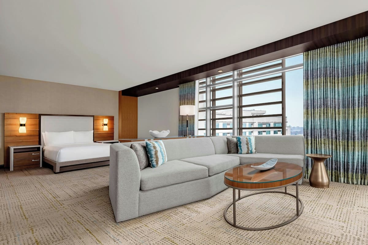 A hotel room with a bed, a sofa, a coffee table, and a nightstand.