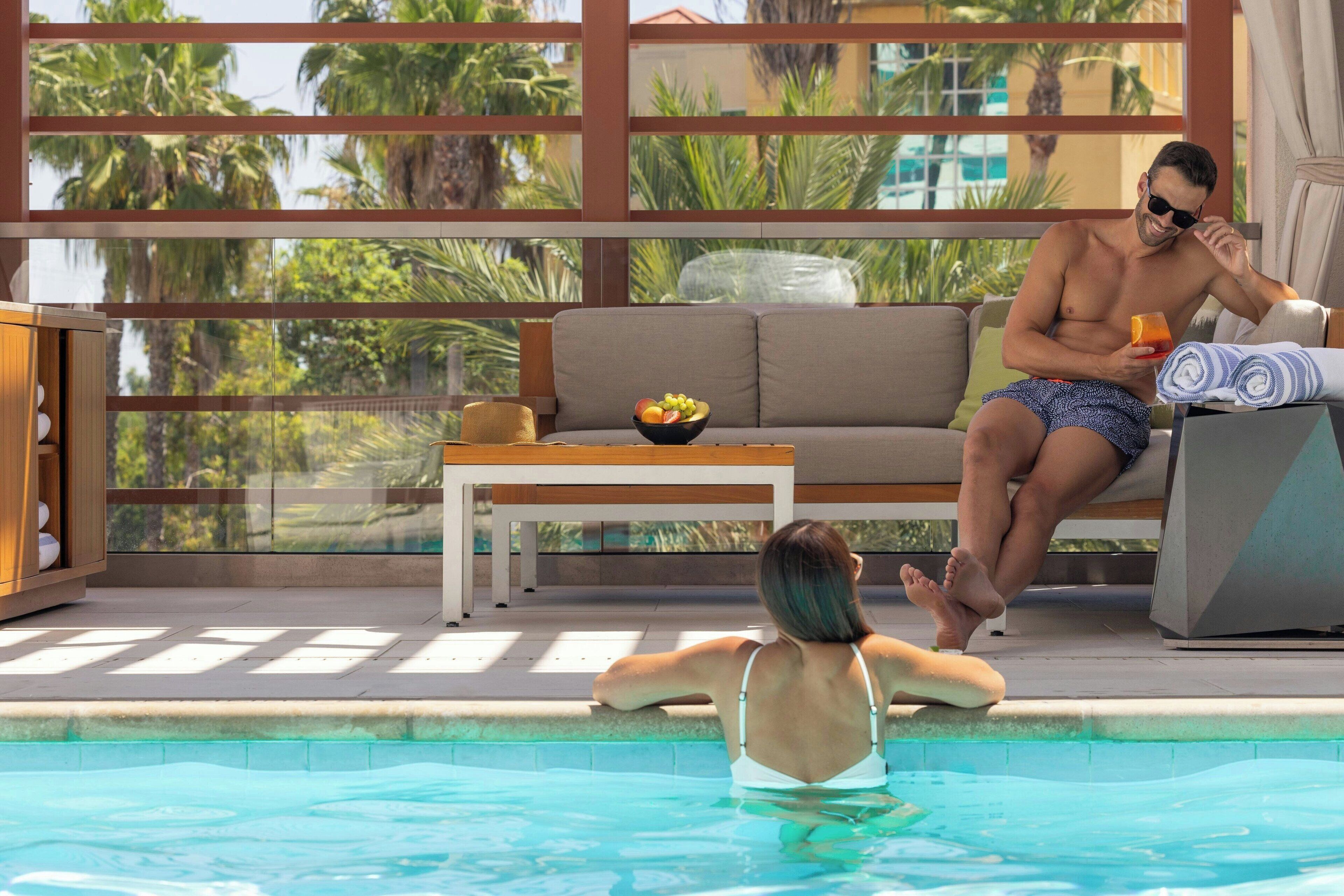 Una piscina al aire libre, camas de piscina con cargo, sombrillas