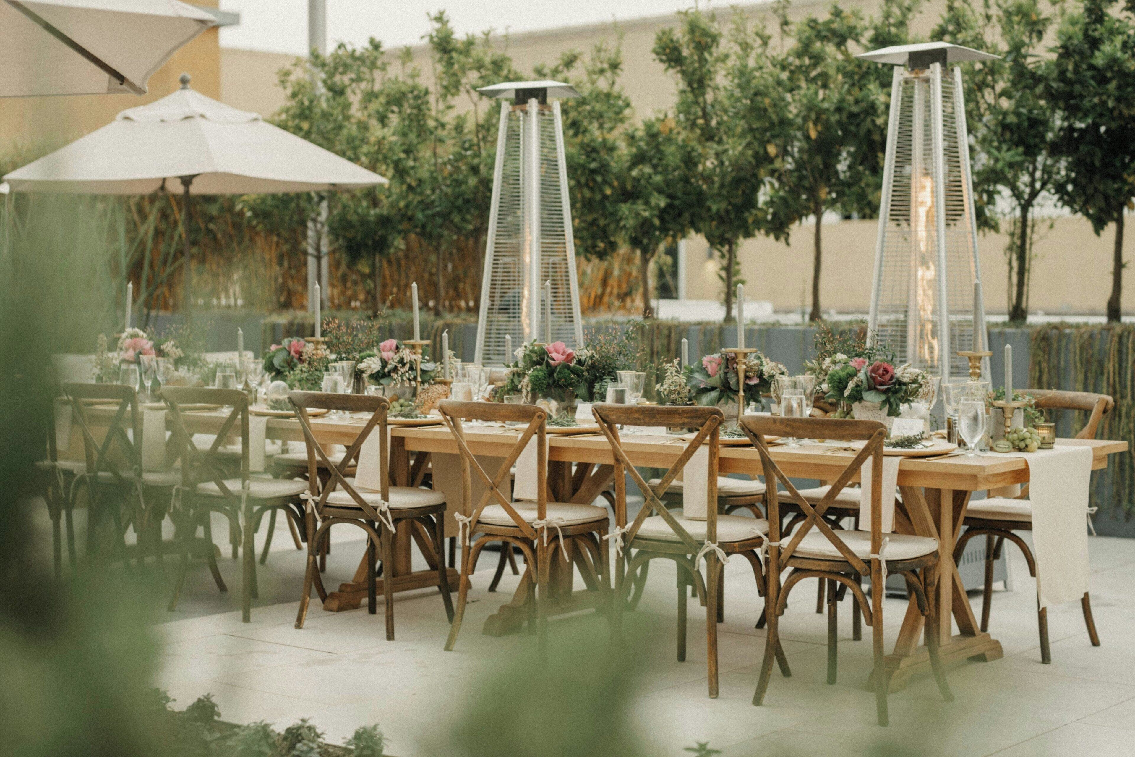 Un espace de restauration en plein air avec des tables et des chaises en bois, entouré de verdure et d’arbres.