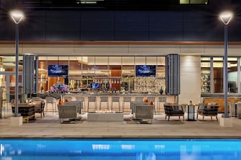 A JW Gardens sign with a wooden slatted design and illuminated letters. at JW Marriott Anaheim Resort
