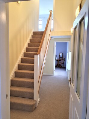 Stairs lead to an upper floor with a door and a dining area.