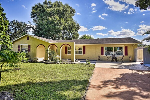 A yellow house with a patio, a small garden, and a large tree in the background. - 8 Mi to Universal: Orlando Studio w/ Fire Pit! (Orlando)