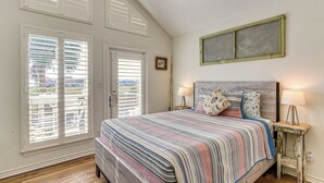 Una camera da letto con un letto grande, due comodini con lampade, un quadro appeso al muro e una finestra con persiane.