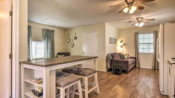 A compact living space with a kitchenette, a dining area with bar stools, a sofa, and a ceiling fan.