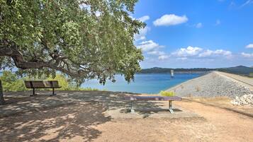 A park with benches and a view of a body of water and a dam.
