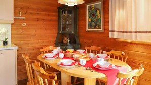 A wooden dining table set with white plates, bowls, and cups, surrounded by wooden chairs.
