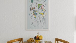 A dining table with breakfast items, a framed abstract art piece, and two wooden chairs.