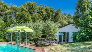 A swimming pool with a wooden deck, a green and white striped umbrella, and a small outdoor seating area with a table and chairs. - Stunning private villa for 7 guests with private pool, TV, terrace and pets allowed (Rosignano Solvay-castiglioncello)