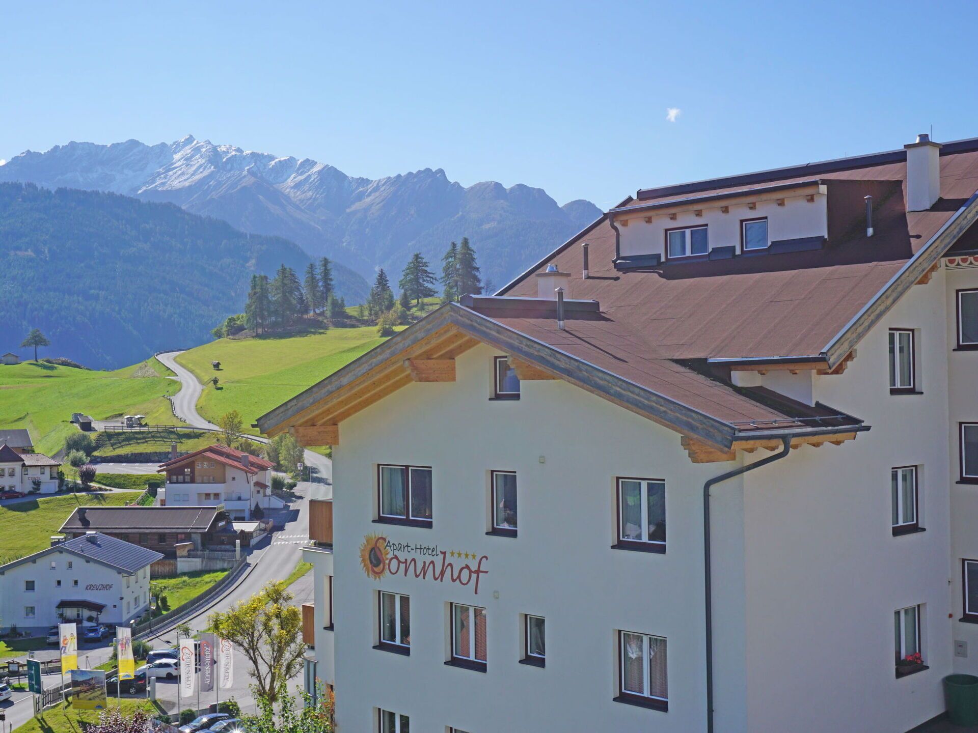 A hotel with a mountain view, multiple windows, and a sign indicating it is a 'Spare-Hotel Sonnhof.'