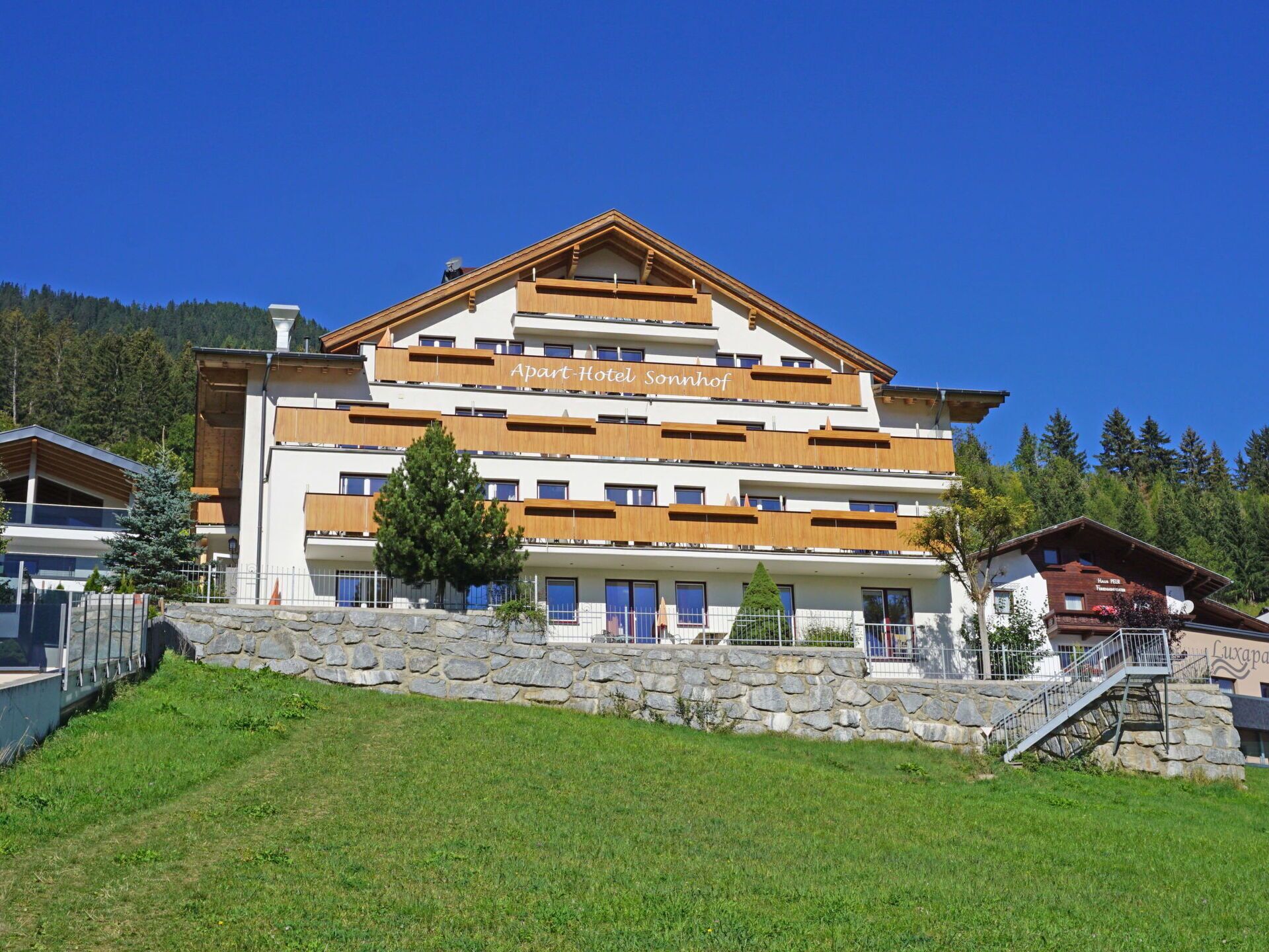A multi-story hotel with a modern design, featuring balconies and a stone facade.